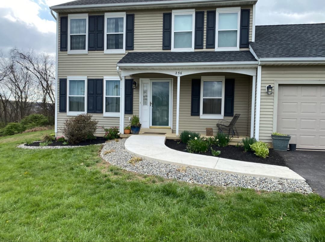 Front view of a suburban home with a landscaped path, garden, and garage.