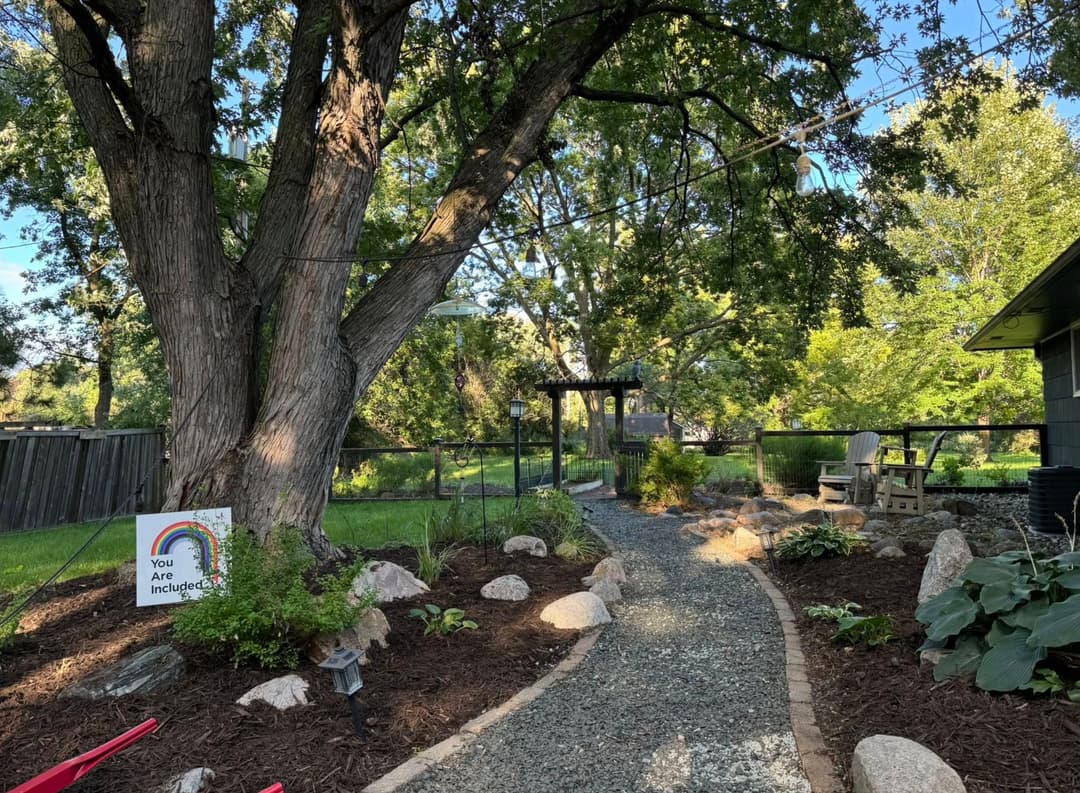 Landscape design featuring gravel mulch along a house with a worker and green lawn.
