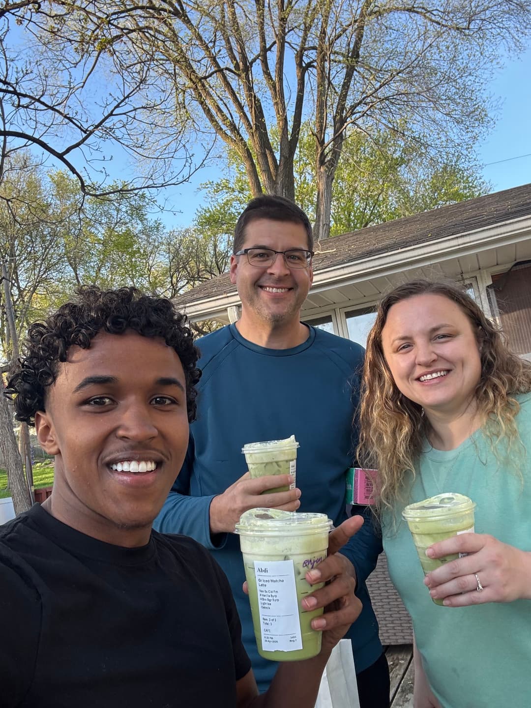 Group enjoying green smoothies outdoors in spring sunshine. Smiling faces and vibrant greenery.