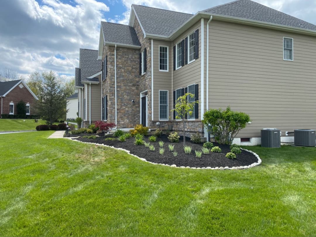 Well-manicured home exterior with stone accents, landscaped garden, and lush green lawn.